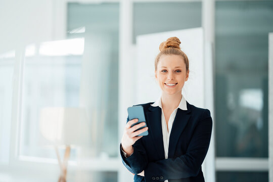 Businesswoman with hair bun holding smart phone at office