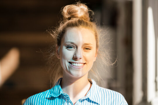 Happy businesswoman with hair bun at home