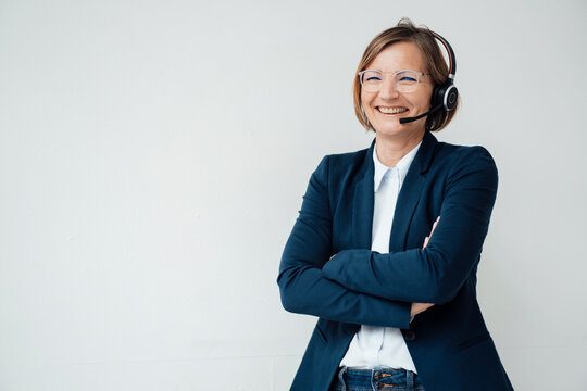 Happy Telecaller Wearing Headset Standing With Arms Crossed Against White Background