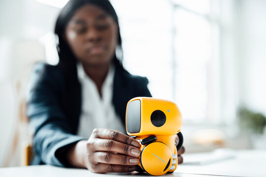 Businesswoman with yellow small toy robot at desk