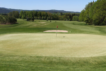 Golf course, meadow with green, bunker and flag