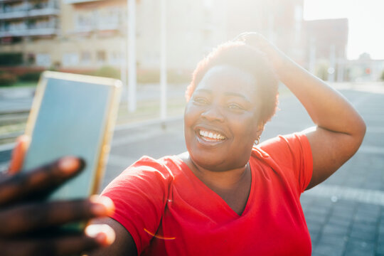 Happy woman taking selfie through smart phone on sunny day