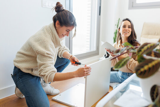 Happy young woman with lover installing furniture at home