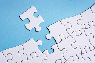 Piece of jigsaw puzzle on blue paper. Directly above. Copy space.