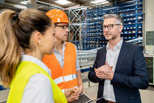 Mature manager planning strategy with colleagues in meeting at factory