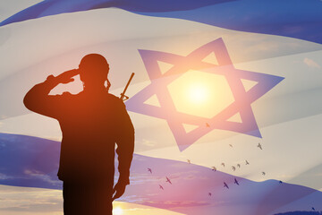 Silhouette of soldier saluting against the sunrise in the desert and Israel flag. Concept - armed...