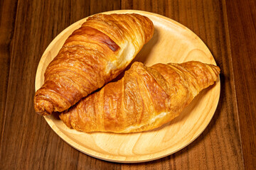 Delicious, fresh croissants on wooden plate.