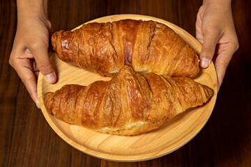 Delicious, fresh croissants on wooden plate.