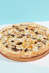 Italian pizza with mushrooms and creamy sauce on coloured background. Mushroom pizza with cheese in minimal style on light blue color. American pizza delivery concept with color backdrop.