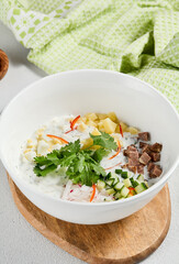 Traditional russian soups - okroshka with fresh vegetables, meat and kefir. Cold summer soup on white table. Aesthetic composition with traditional russian food and spices, textile