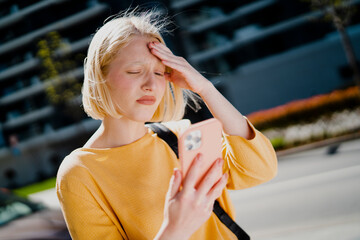 Upset woman using the phone. Girl walking on the street checking phone