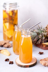 Tepache drink in glass bottles with reusable drinking straws and glass pitcher on kitchen table
