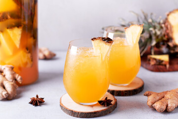 Tepache drink in glass with ice, pineapple and glass pitcher on kitchen table