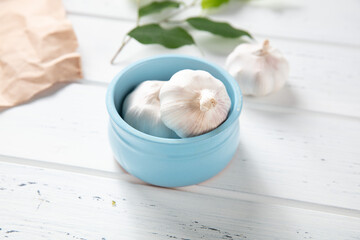 Fototapeta na wymiar Garlic in a bowl on a wooden background. Nice garlic. Photo for the catalog