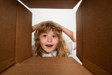 Funny excited child unpacking and opening the carton box looking inside. The little kids unboxing gift inside view. Open box and delivery parcel for children. - obrazy, fototapety, plakaty