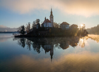 Lake Bled on a foggy and misty autumn morning. Vivid sunrise on a beautiful autumn day.