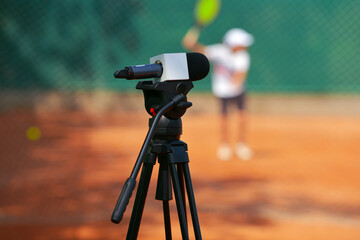 TV industry. A microphone is placed on a video camera tripod with a tennis match game in...