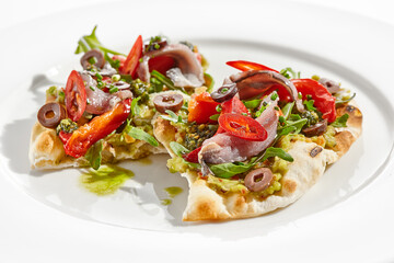 Tapas with avocado cream, anchovy, paprika and kalamata olives on focaccia. Bruschetta with guacamole and anchovy isolated on white background. Appetizer contemporary concept. Fish antipasti.