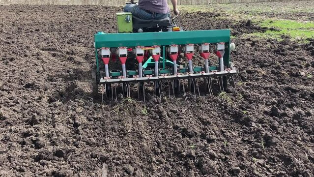 Tractor sowing seeds with seeder driller in field. Process of sowing cereals and other crops. Agricultural field, sowing work in the field. Tractor with seeder performing seeding. High quality 4k foot