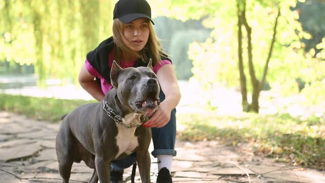 Pointing finger, command of attack, animal is barking. Young woman is on the walk with her pitbull dog outdoors
