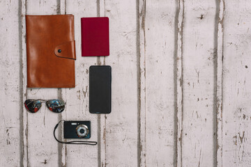 top view still life travel. Light wood background. Personal documents, passport, sunglasses and compact camera for trip.