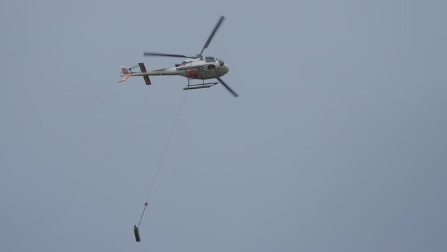 A heavy-lift helicopter transports stones for the hiking trail construction. Slow-motion.