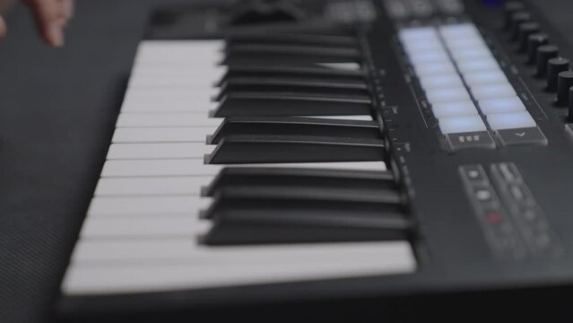 Closeup of male hands composing music using a midi controller launchpad key.