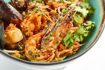 Japanese soba with seafood cooked on wok in asian style on white background. Noodle seafood in ceramic bowl. Indonesian wok with prawn, mussels and soba noodles. Spicy thai dish with shrimp and udon.
