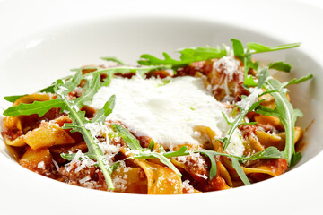 Italian pasta pappardelle with bolognese sauce  and parmesan isolated on white background. Pasta tagliatelle with meat ragu and creamy espuma with arugula. Minced beef in tomato sauce with pasta.