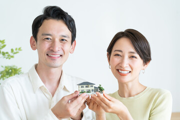 住宅の模型を持つ日本人カップル