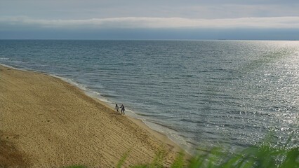 Two people running sea shore together. Ocean wave on beach landscape aerial view