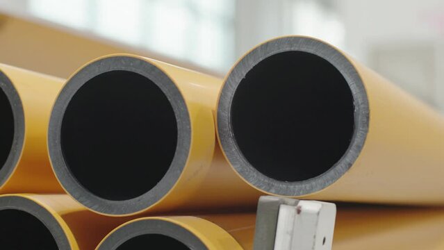 Stack of plastic pressure gas pipe, PE100, polyethylene pipe in close-up. Smooth and round. International standards, ASTM D2513. HDPE plastic product. Pan and tilt up.