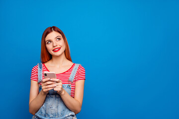 Portrait of minded positive girl hold telephone look interested empty space isolated on blue color...