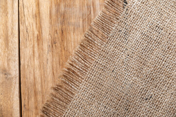 The burlap lies on the tabletop of a wooden table. Rough cloth on top of rough boards. Top view