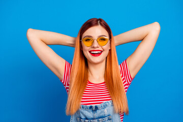 Photo of funny charming woman wear jeans outfit dark glasses arms behind head isolated blue color background