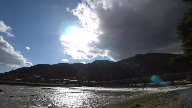 KYOTO, JAPAN - DEC 2021 : View of Togetsukyo (bridge) and Katsuragawa (river) in autumn leaves season. Wooden bridge spans the Katsura River in front of Arashiyama Mountain. Time lapse shot in daytime