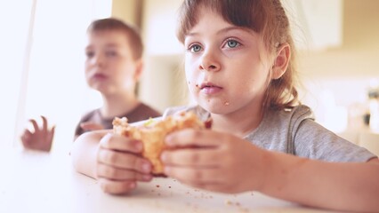 children eat burgers. fast food burger. a group of small children in the kitchen greedily eat fast food burgers. big sun family small kids having breakfast in the morning in the kitchen eating burger