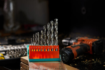 Close up of a metal drill bit set at workshop, carpenter chooses a drill for drilling a wooden...