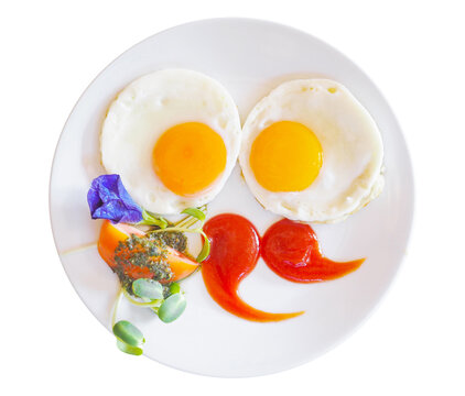 Two fried egg with tomato sauce and vegetables on white dish