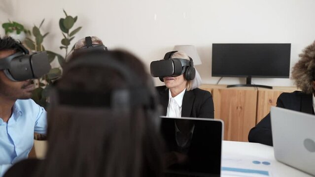 business people in virtual reality glasses try 3D application for VR headset in modern office. Team of workers using innovative future technology through VR headsets- group of diverse generations -