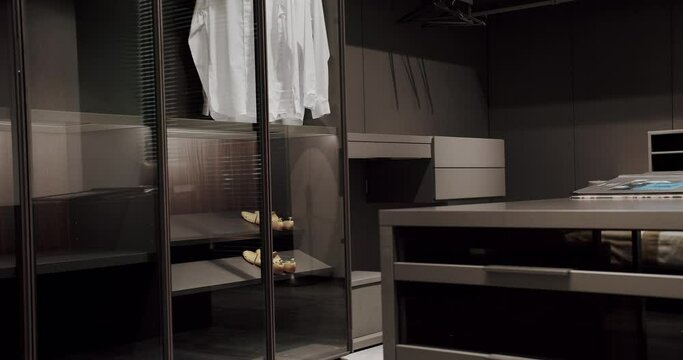 Black wardrobe with Sliding Black Doors. , Luxury Bedroom With Walk In Closet. Dressing room with shirts. Elegant Wooden Built Walk In Closet Decoration. Luxury Dressing Room. Modern Sliding Doors.