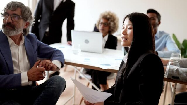 group of business people in a meeting in the office, focus on asian woman. Concentrated diverse sit at desk brainstorm working on laptop together