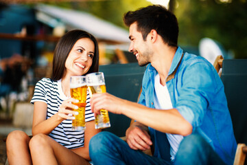 Young couple at a summer bar toast with beer