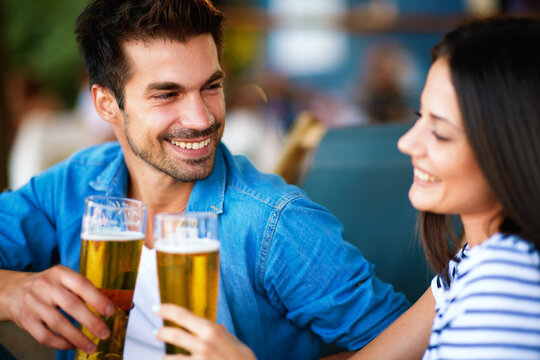 Young couple at a summer bar toast with beer