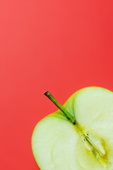 Close up view of juice green apple isolated on red.