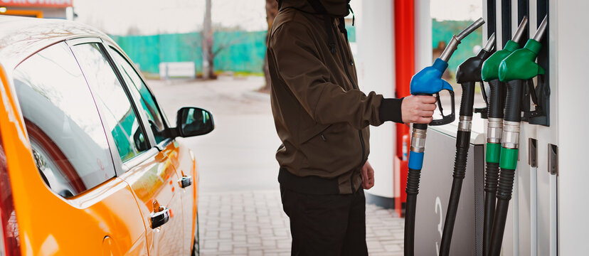 Unrecognizable man refueling car from gas station filling benzine gasoline fuel in car at gas station. Petrol high prices concept