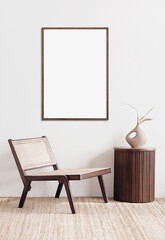 Vertical poster mockup with wooden frame in living room interior with chair, dried grass on table and Scandinavian style decor on empty white wall background. Home staging and minimalism concept