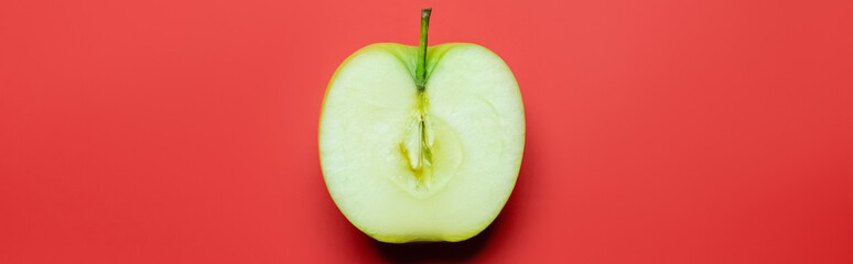 Top view of cut green apple on red background, banner.