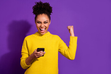 Portrait of delighted successful girl raise fist celebrate follow isolated on purple color...