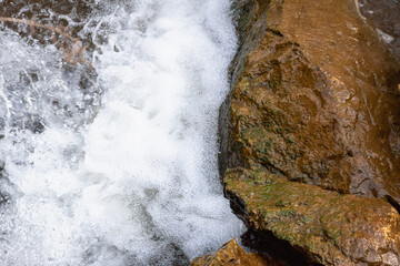 The mountain river beats against large stones, boulders.